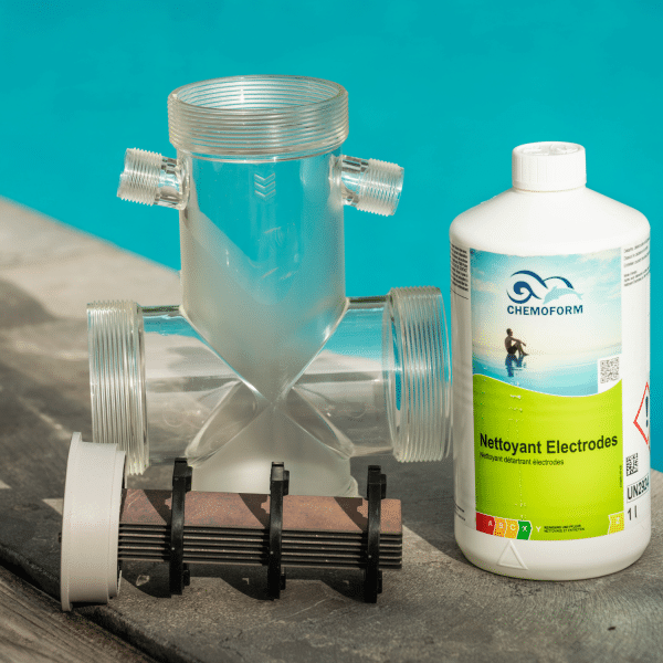 Bouteille de nettoyant électrodes Chemoform posée au bord d’une piscine avec une cellule d’électrolyseur démontée et entartrée